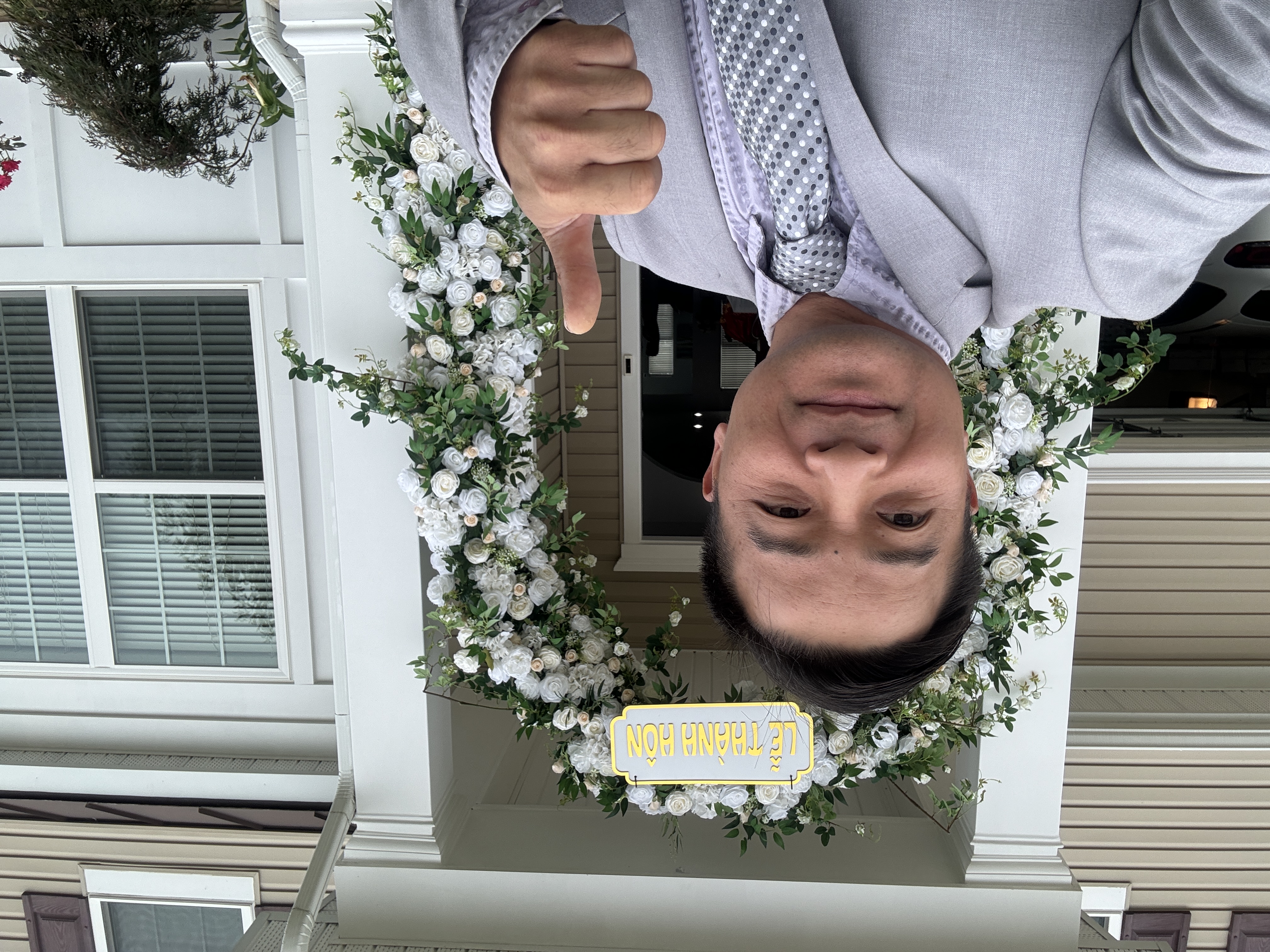 DJ MC Thinh in a suit at a wedding entrance decorated with white flowers